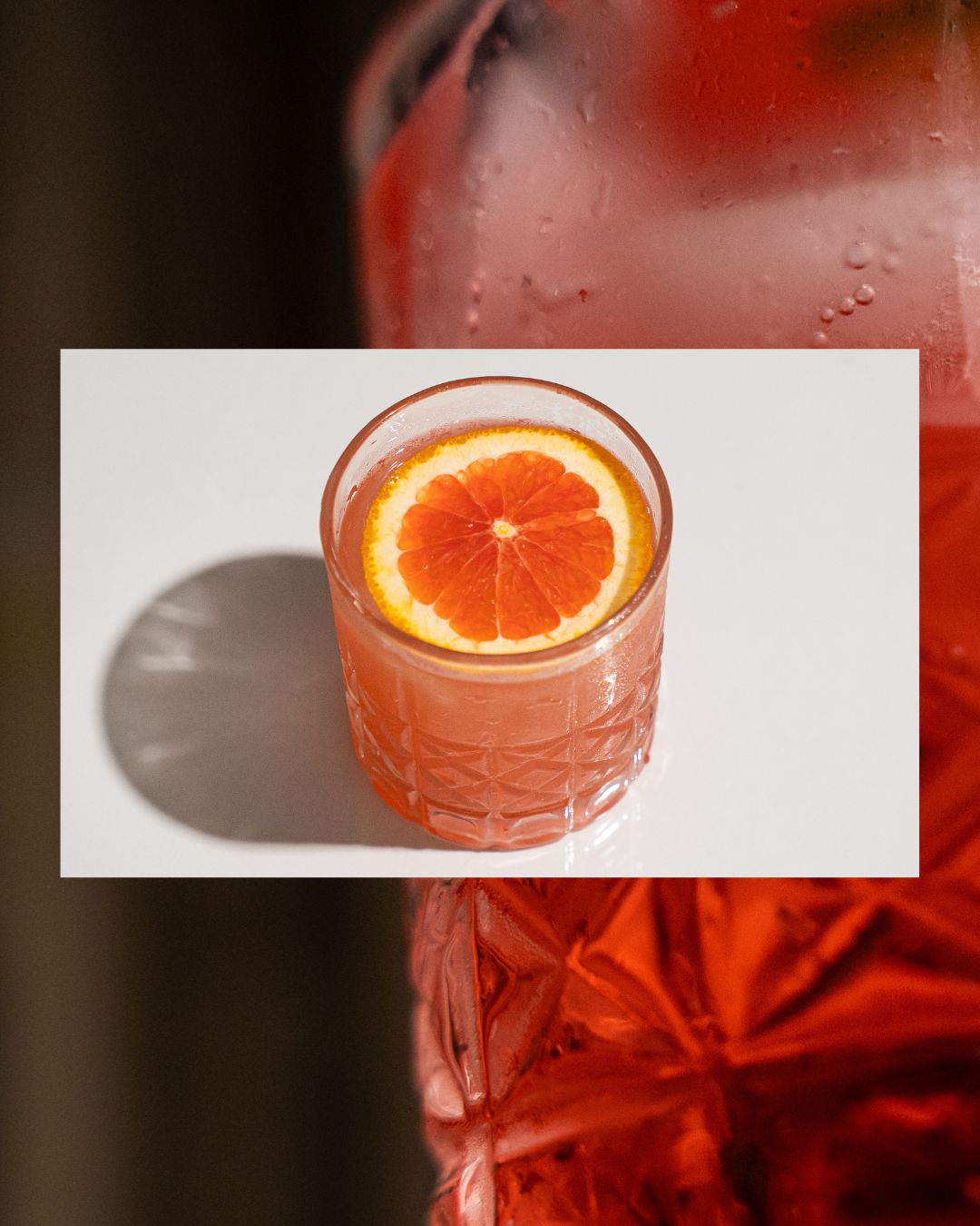 Overhead shot of a pink citrus cocktail topped with a grapefruit wheel.