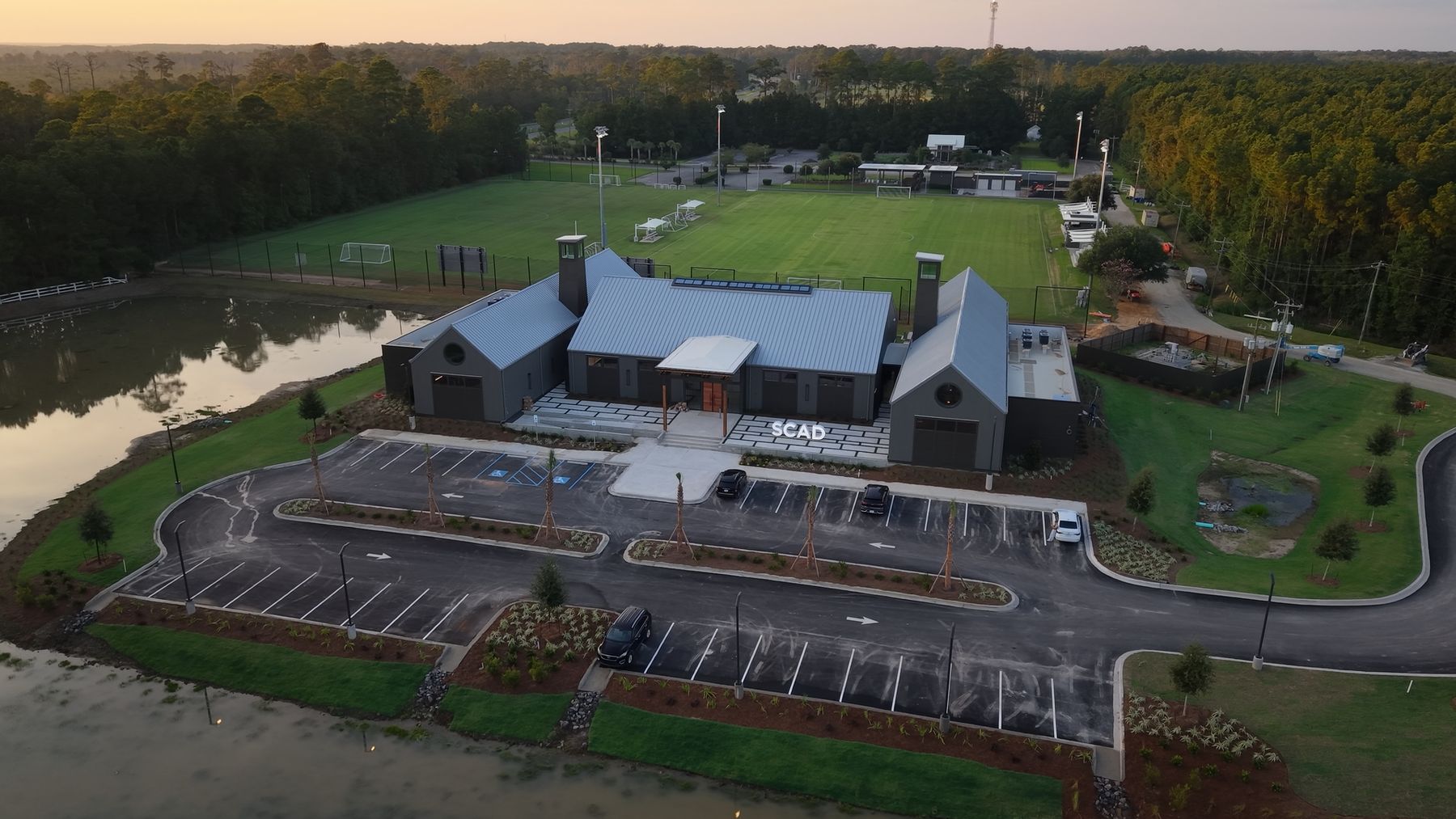 Aerial view of a new SCAD athletics building and soccer fields at sunrise.