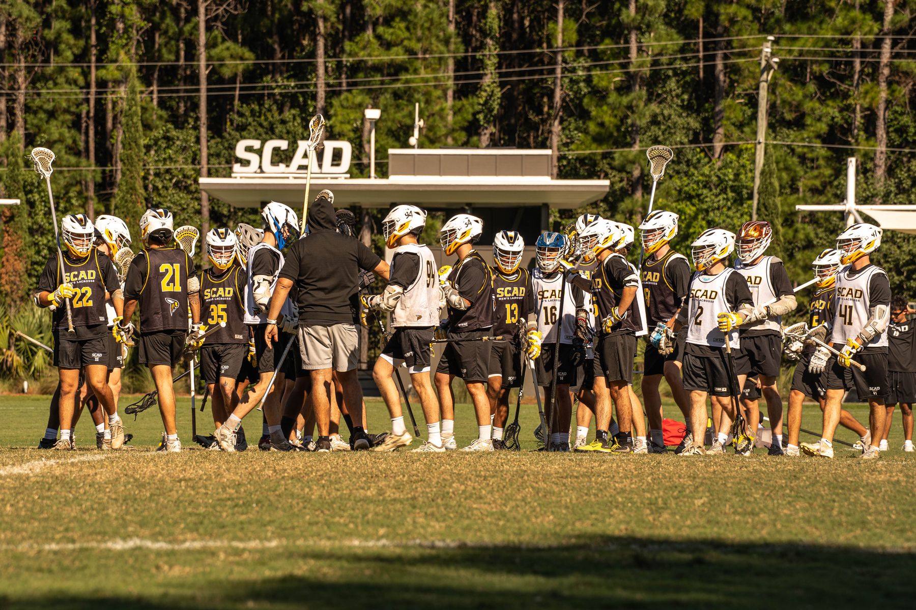 SCAD men’s lacrosse players gathered on the field during an alumni event.